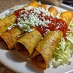 Four crispy, rolled potato tacos smothered in red salsa and crumbled white cheese, served on shredded lettuce.