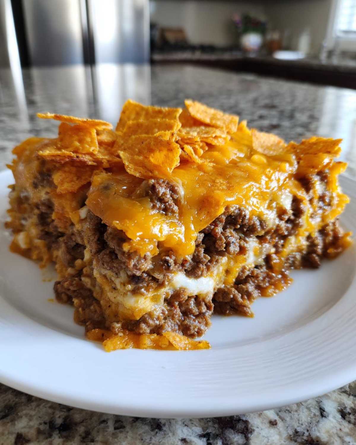 A close-up slice of Dorito Casserole layered with seasoned ground beef, melted cheese, and topped with crushed Doritos.