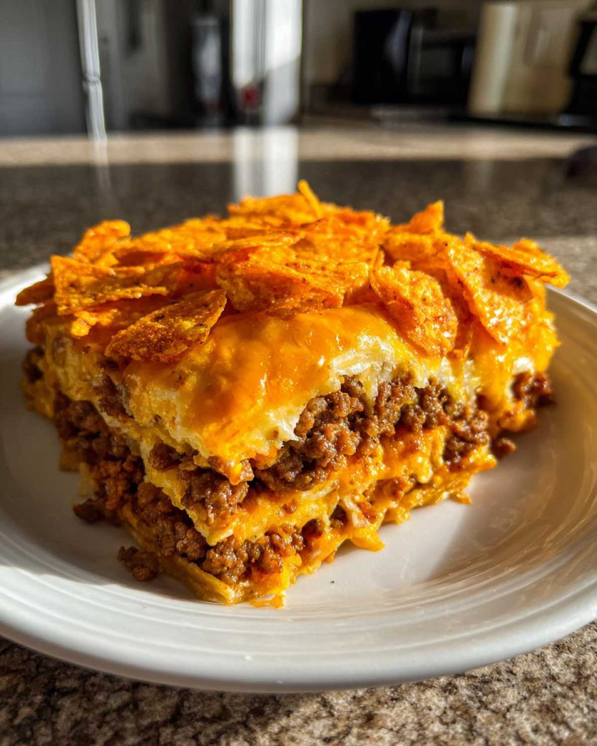 A thick slice of Dorito Casserole layered with seasoned ground beef and melted cheese, topped with crushed Doritos.