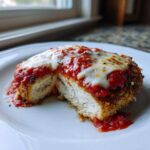 A cross-section view of Easy Chicken Parmesan showing the breaded crust, white chicken meat, marinara sauce, and melted mozzarella cheese.