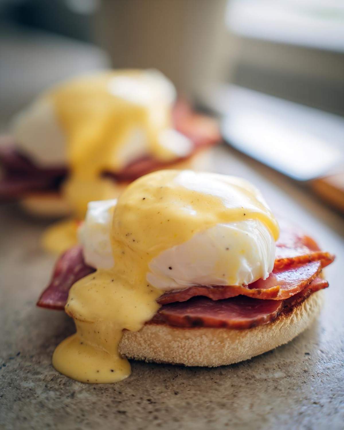 Close-up of a perfectly made eggs benedict featuring a poached egg, ham, and rich hollandaise sauce.