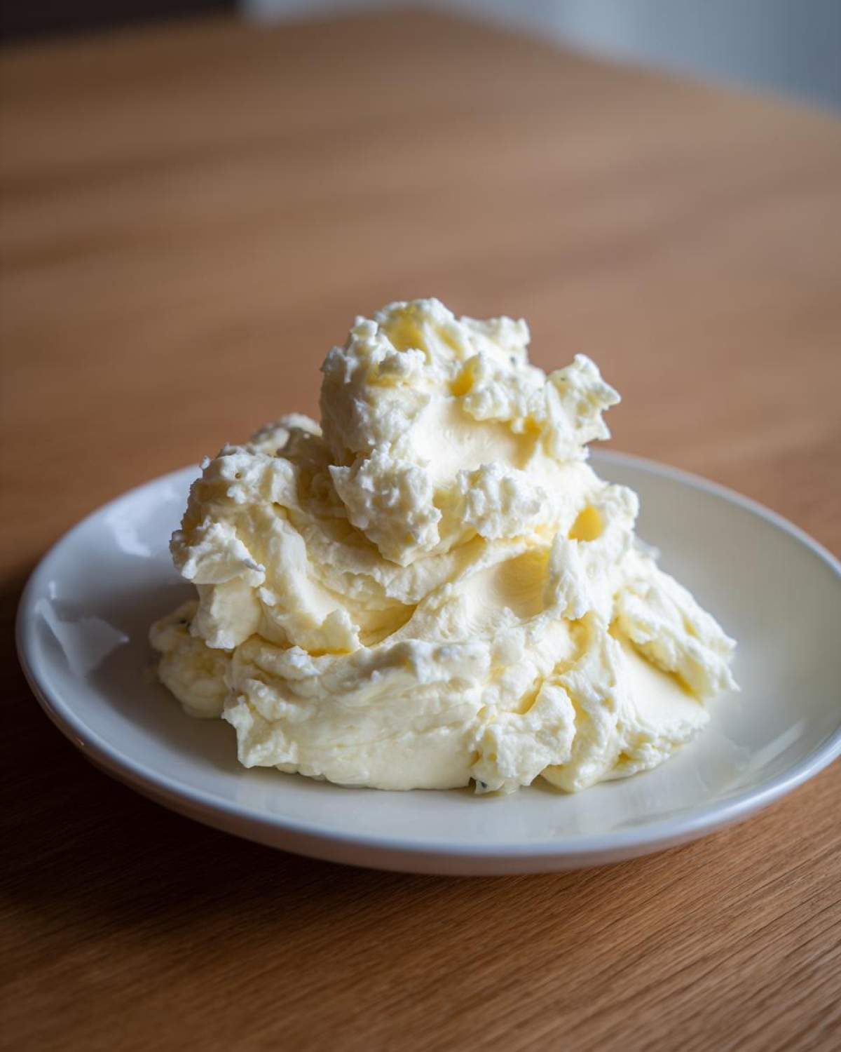 A mound of creamy, fluffy Boursin mashed potatoes served on a small white plate.