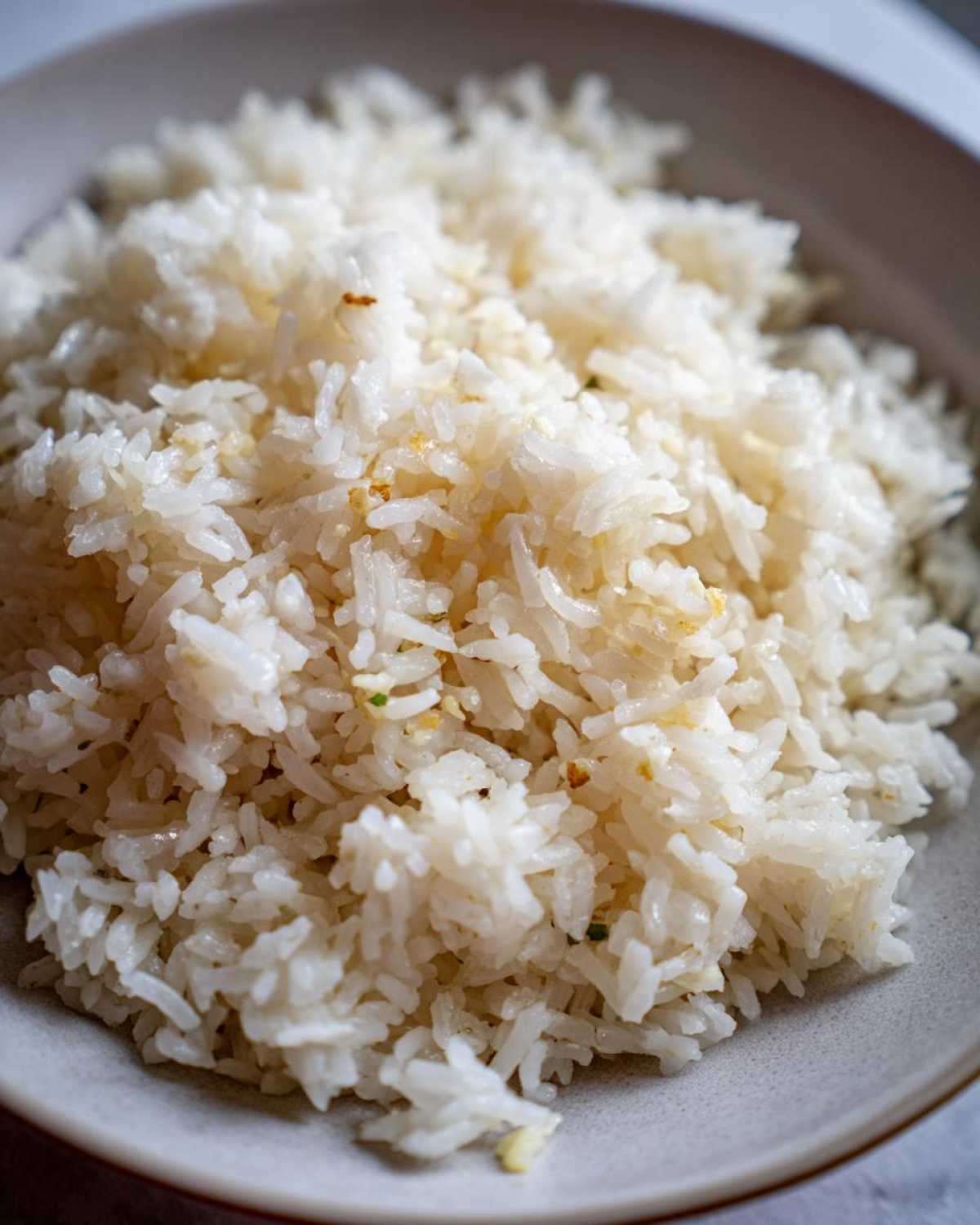 Close-up of fluffy white butter rice seasoned lightly, served in a light gray bowl.