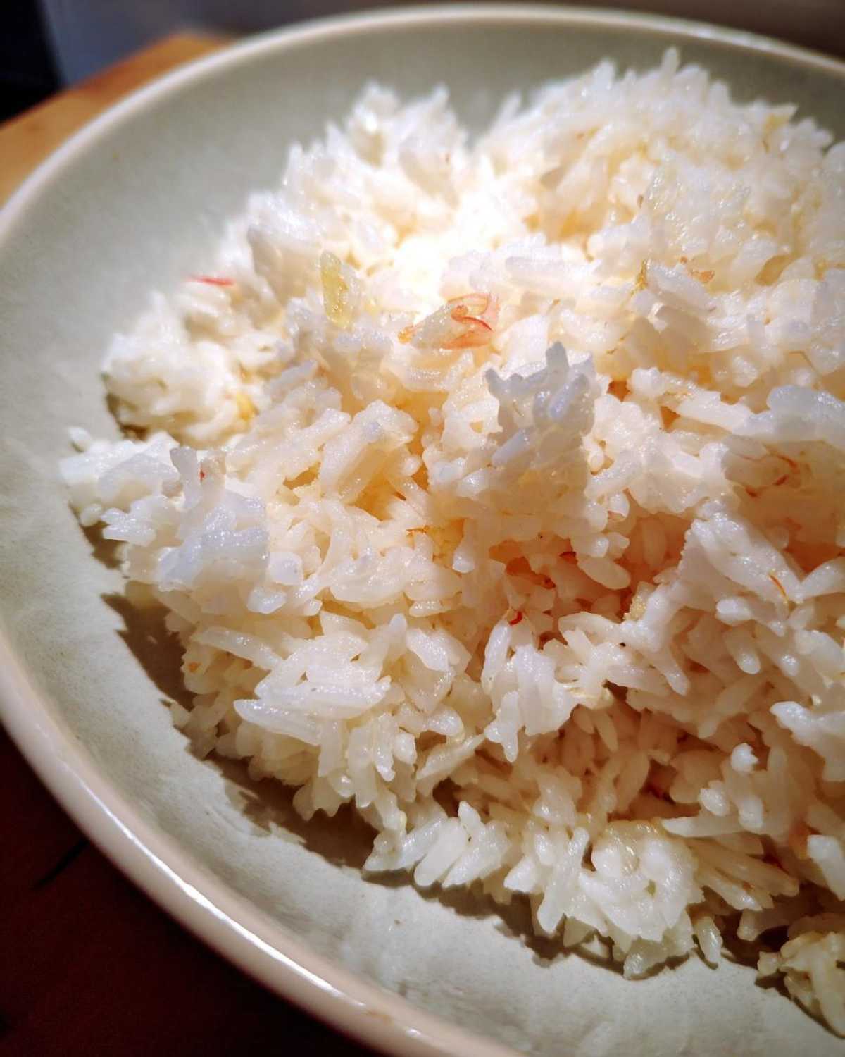 Close-up of fluffy white rice mixed with melted butter, served in a light green bowl, showcasing the butter rice texture.