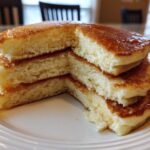 Close-up of a stack of four incredibly fluffy pancakes cut to show the airy interior.