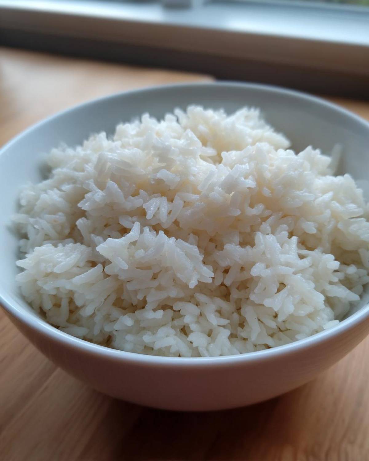 Close-up of fluffy white rice served in a white bowl, ready to be made into cheesy rice.
