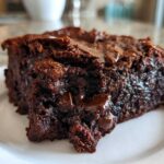 A close-up, decadent slice of fudgy black bean brownies showing melted chocolate chips on a white plate.