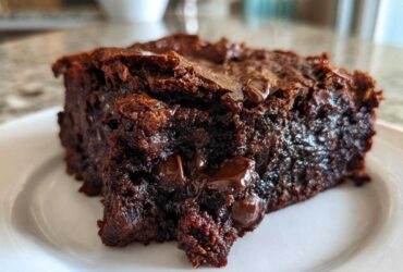A close-up, decadent slice of fudgy black bean brownies showing melted chocolate chips on a white plate.