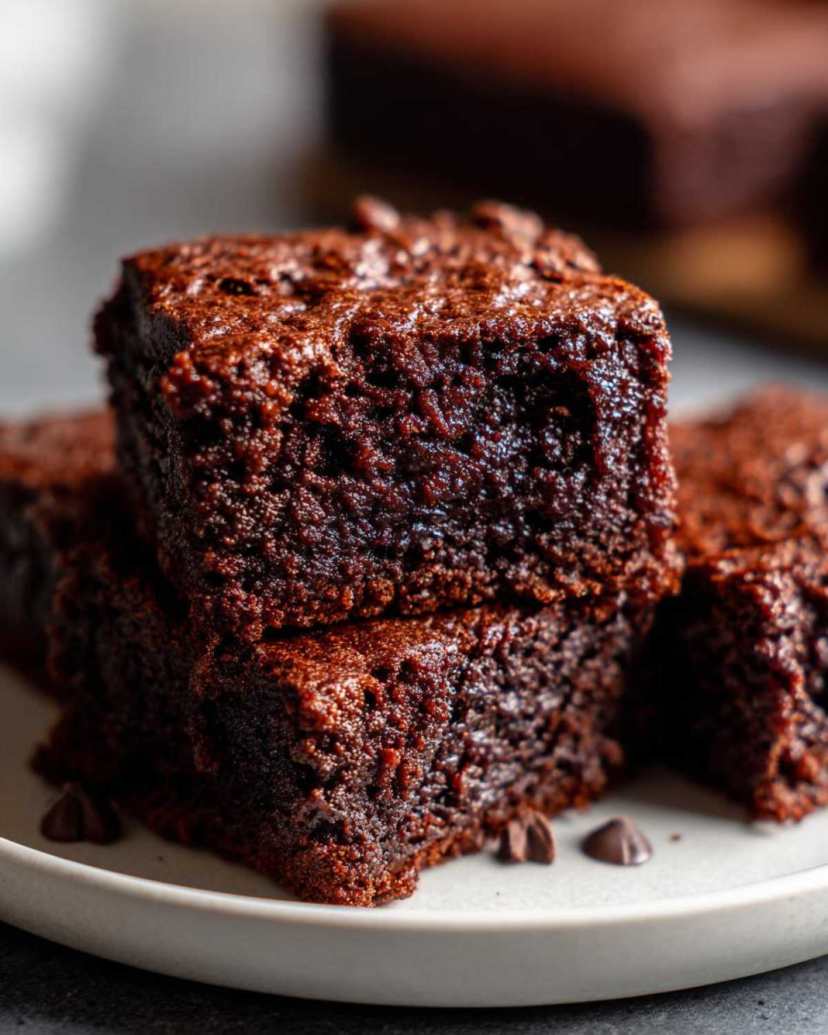 Close-up of stacked, fudgy gingerbread brownies showing their rich, dark texture and chocolate chips.