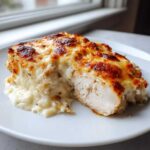 A cross-section view of a juicy Garlic parmesan chicken bake topped with melted, browned cheese sauce.