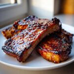Close-up of perfectly cooked, glazed pork steak pieces stacked on a white plate.