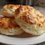 Three golden brown, fluffy cloud bread pieces stacked on a white plate, showing a light, airy interior.