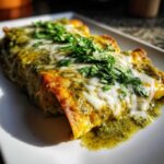 Close-up of delicious green chile chicken enchiladas covered in melted white cheese and fresh cilantro.