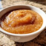 Close-up of rich, spiced homemade applesauce served in a small white bowl.