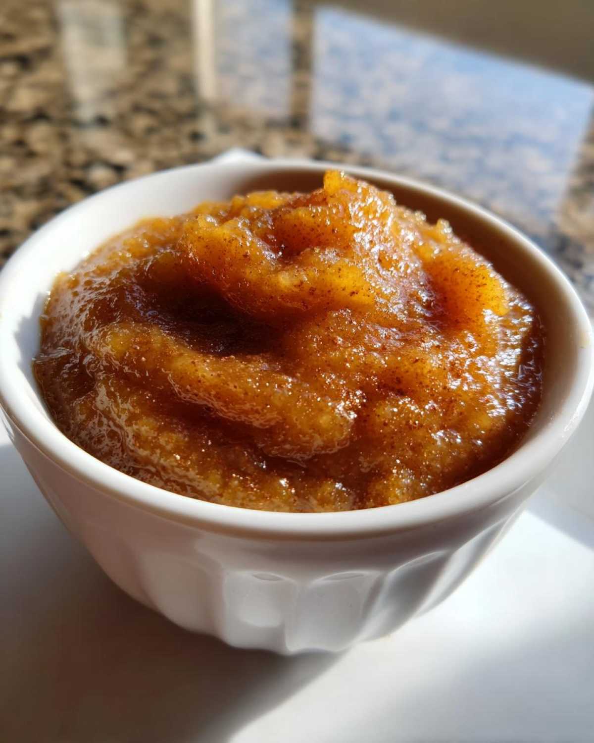 Close-up of rich, spiced homemade applesauce served in a small white ramekin.