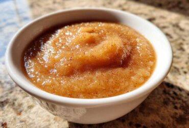 Close-up of rich, spiced homemade applesauce served in a small white bowl.