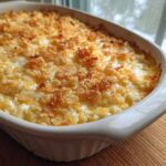 A creamy, baked hot chicken salad casserole topped with golden, crunchy cornflakes, served in a white dish.