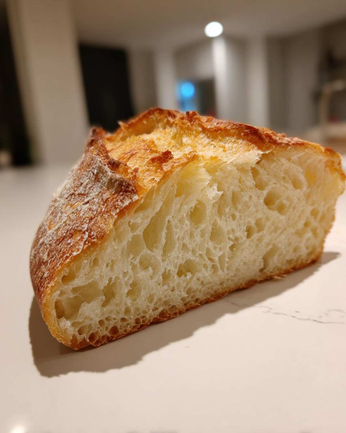 Close-up of a slice of Italian bread showing its open, airy crumb structure and golden crust.