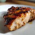 Close-up of a juicy, grilled chicken breast showing the moist interior and caramelized glaze from the chicken marinade.