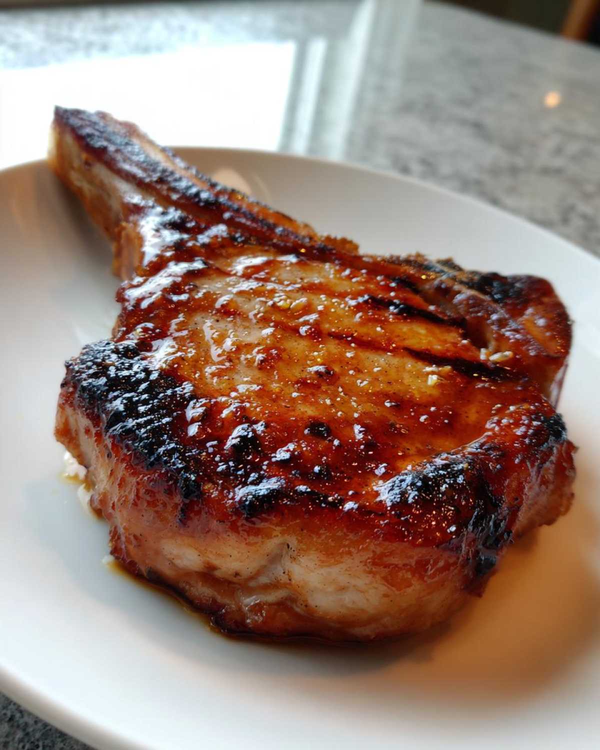 Close-up of a thick, bone-in pork chop cooked to perfection with a glossy, caramelized glaze, showing the results of the best marinade for pork chops.