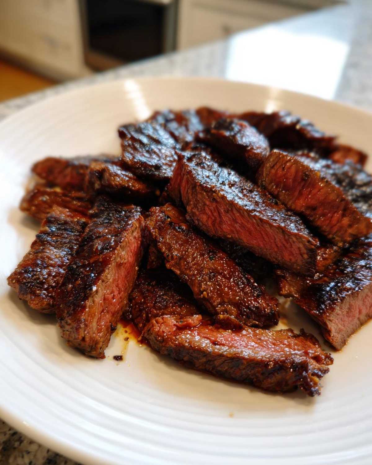 Close-up of perfectly grilled and sliced steak showing a medium-rare center, likely prepared with carne asada marinade.
