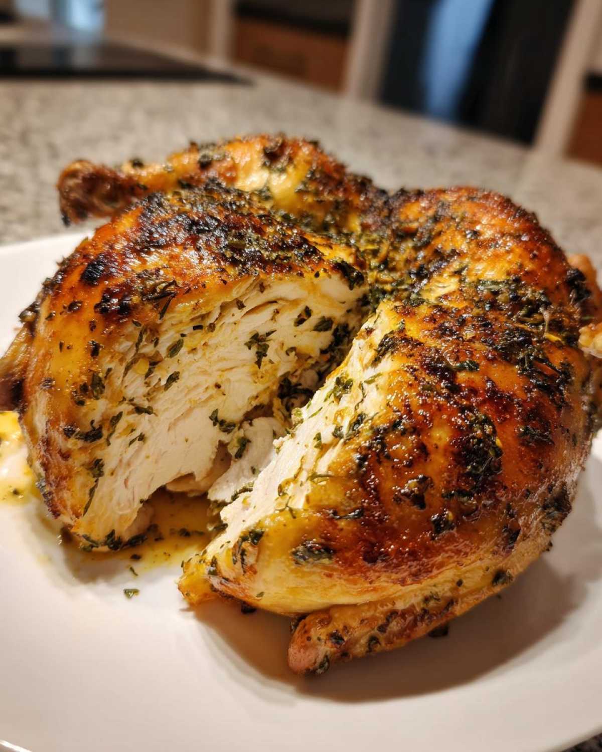 A perfectly roasted spatchcock chicken, cut open to reveal moist white meat and crispy, herb-crusted skin.