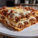 A close-up of a hearty slice of lasagna with cottage cheese, meat sauce, and melted mozzarella topping.