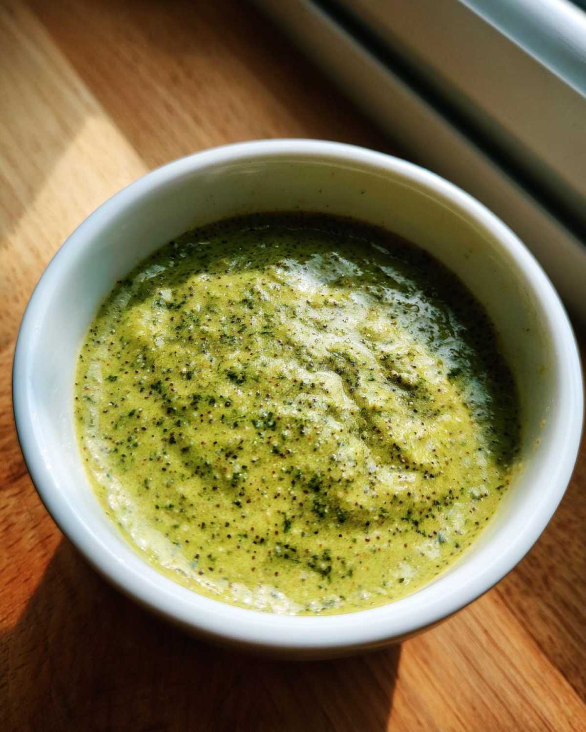 A close-up view of vibrant green matcha chia pudding speckled with dark chia seeds in a white bowl.