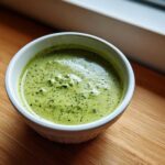 Close-up of vibrant green matcha chia pudding with visible chia seeds in a white bowl.