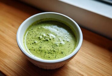 Close-up of vibrant green matcha chia pudding with visible chia seeds in a white bowl.