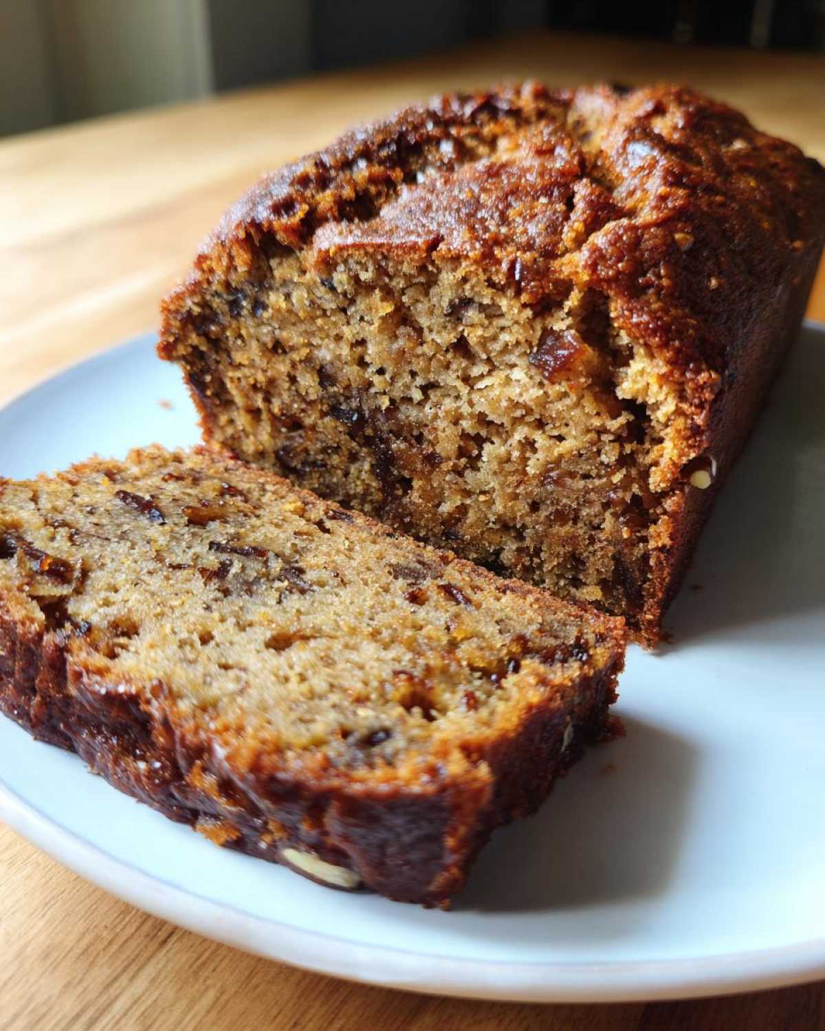 Close-up of a moist slice cut from a loaf of date nut bread, showing the rich texture and dark fruit pieces.