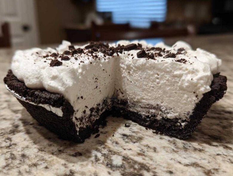 Close-up of a slice missing from a no-bake ice cream pie showing thick white filling and dark crust.