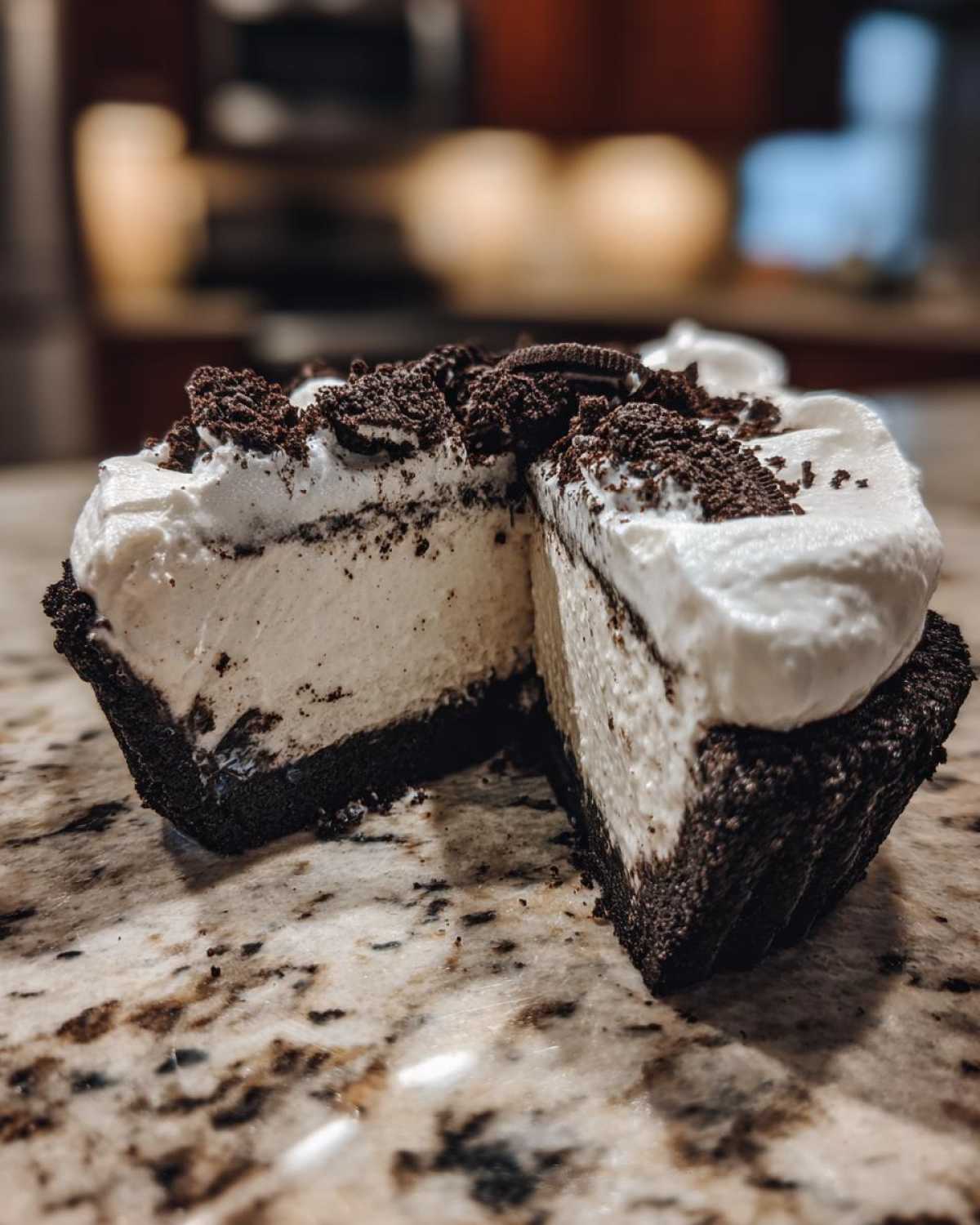 A slice cut from a no-bake ice cream pie showing a thick, creamy filling, dark cookie crust, and whipped topping with cookie crumbles.