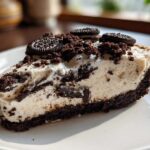 Close-up of a decadent slice of no-bake Oreo cheesecake showing the creamy filling and dark cookie crust.