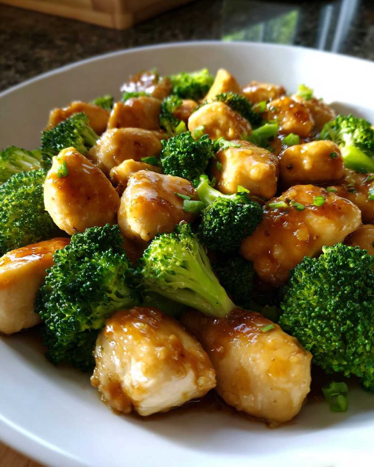 Close-up of tender chicken pieces coated in a savory glaze mixed with bright green broccoli florets, a perfect chicken and broccoli meal.