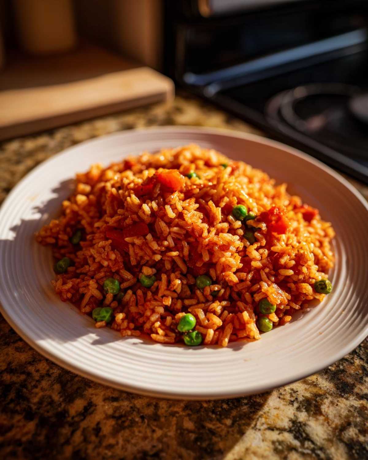 A close-up of a white plate piled high with savory, orange-red Spanish rice mixed with bright green peas.