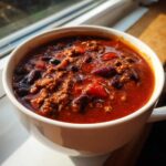 Close-up of a rich, red bowl of chili with ground meat and kidney beans, perfect for the best chili recipe.