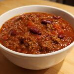 Close-up of a hearty bowl of rich, red crockpot chili featuring ground meat and kidney beans.