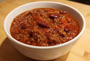 Close-up of a hearty bowl of rich, red crockpot chili featuring ground meat and kidney beans.