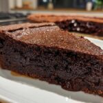A close-up slice of rich, dark chocolate hot fudge pie showing a gooey center.