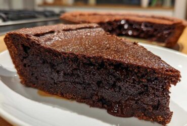 A close-up slice of rich, dark chocolate hot fudge pie showing a gooey center.