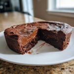 A rich, dark chocolate hot fudge pie with a slice removed, revealing a molten, gooey center.