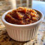 Close-up of thick, rich brown pear butter served in a small white fluted ramekin.