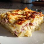 A square serving of creamy scalloped potatoes and ham, baked with a golden, bubbly cheese crust.