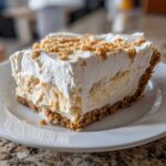 A thick slice of creamy peanut butter pie with a graham cracker crust and whipped topping.