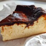 A close-up slice of creamy Basque cheesecake showing its signature dark, caramelized top.