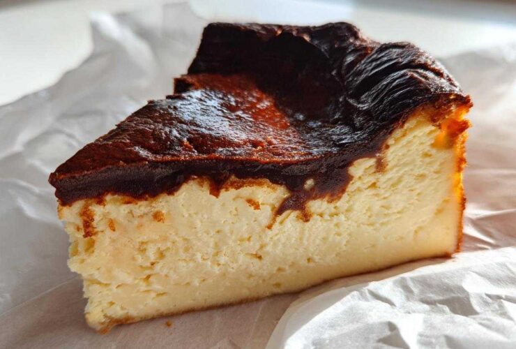 A close-up slice of creamy Basque cheesecake showing its signature dark, caramelized top.
