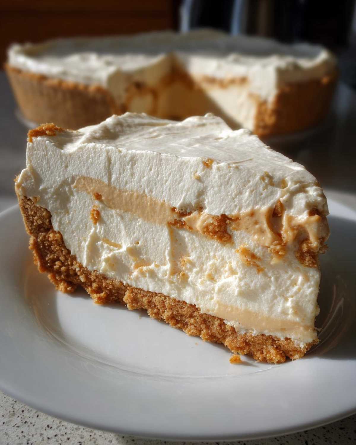 A close-up slice of no-bake peanut butter pie with a thick graham cracker crust and creamy filling.