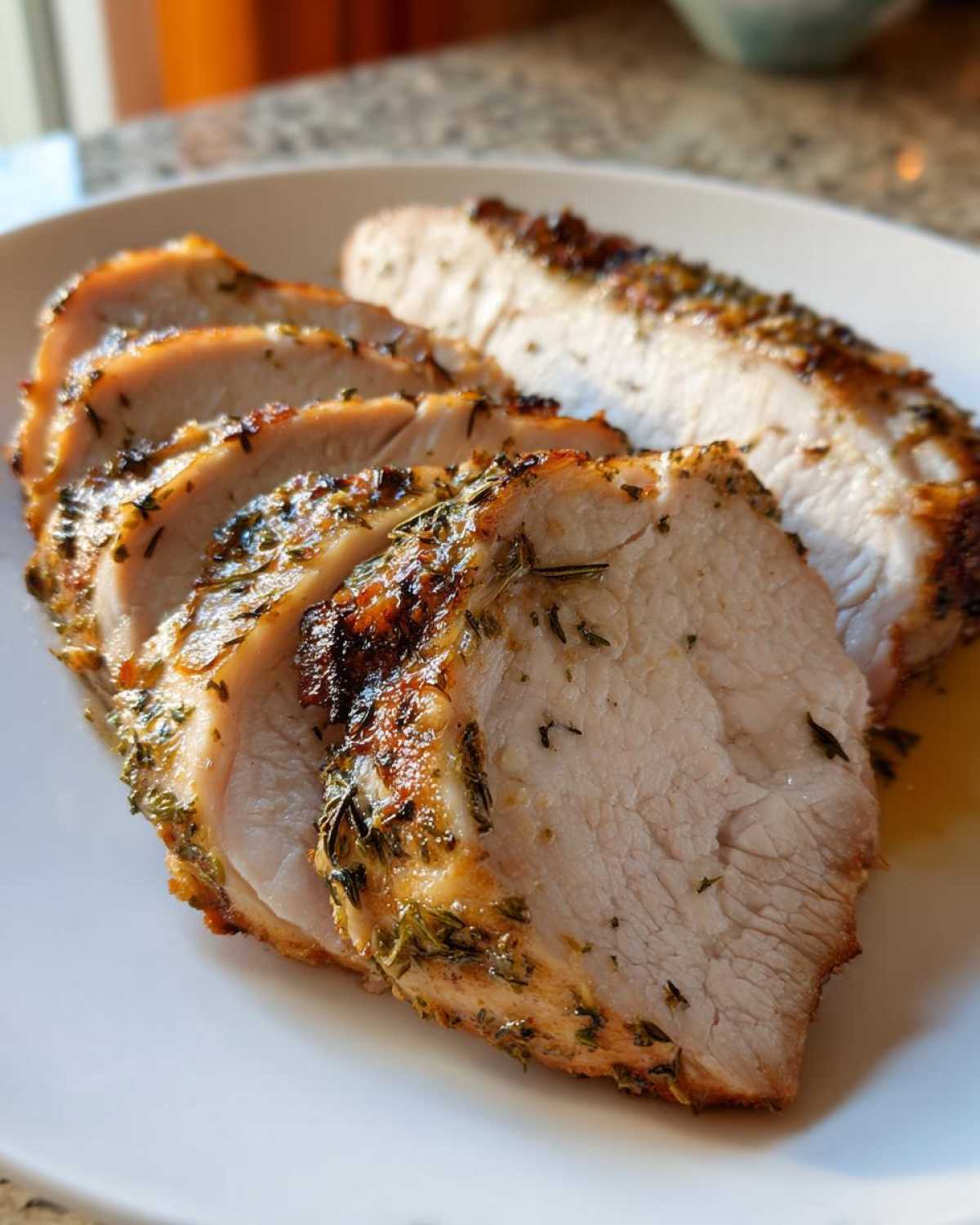 Close-up of juicy, sliced slow cooker turkey breast seasoned with visible herbs.