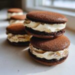 Close-up of two stacked, soft tiramisu cookies filled with rich cream and dusted with cocoa powder.